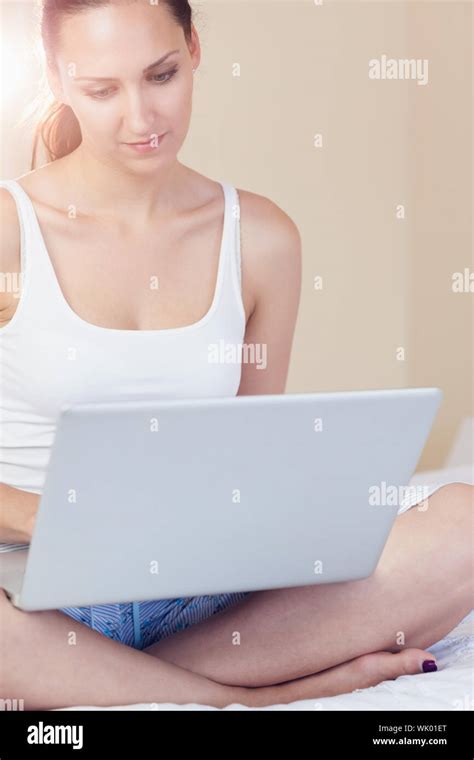 Content Brunette Sitting On Bed Using Her Laptop Stock Photo Alamy