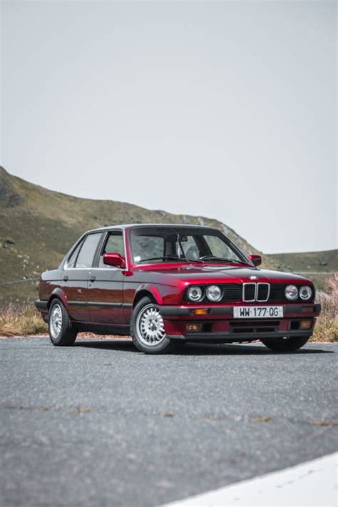 A Red Bmw E30 Sedan Parked On The Side Of The Road · Free Stock Photo