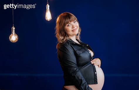 Topless Pregnant Woman In Leather Shirt Posing Against Blue Wall 이미지