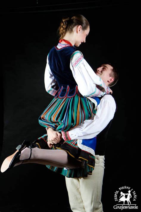 A Man And Woman Dressed In Traditional Clothing Are Dancing With One