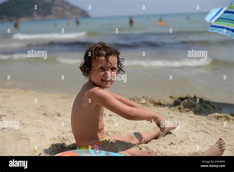 Sonriente niña jugando en la arena de la playa de Thassos Grecia