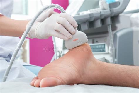 Doctor Conducting Ultrasound Examination Of Patient`s Foot In Clinic