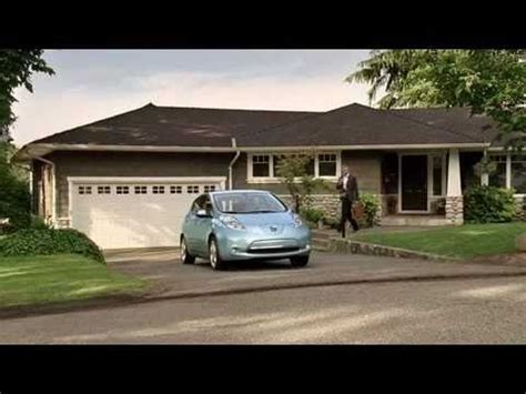 A Blue Car Is Parked In Front Of A House With Two People Walking By It