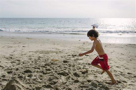 Boy Runs Along The Seashore Paper Airplane In Hand By Stocksy