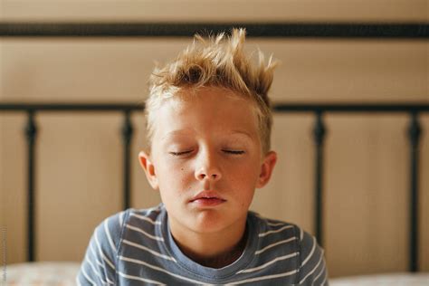 Very Sleepy Boy Sits Up In Bed In The Morning By Stocksy Contributor