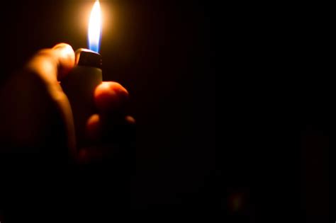 Premium Photo Close Up Of Hand Holding Lit Candle In Darkroom