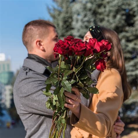 Homme Embrassant Et Embrassant Une Femme Avec Des Fleurs Photo Gratuite