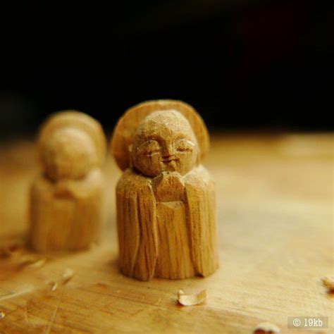 Two Small Wooden Figurines Sitting On Top Of A Wooden Table Next To