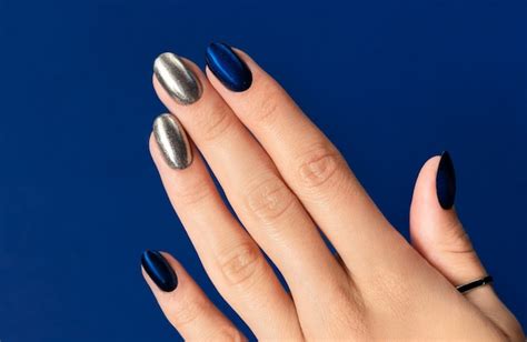 Mano de mujer con manicura de moda brillo sobre fondo azul diseño de