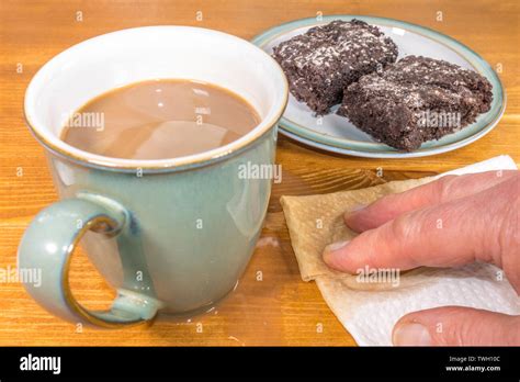 Una Taza Taza De Té Con Una Mano De Limpiar Un Derrame En Una Tabla