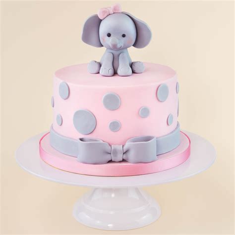 A Pink And Gray Polka Dot Cake With An Elephant Figurine Sitting On Top