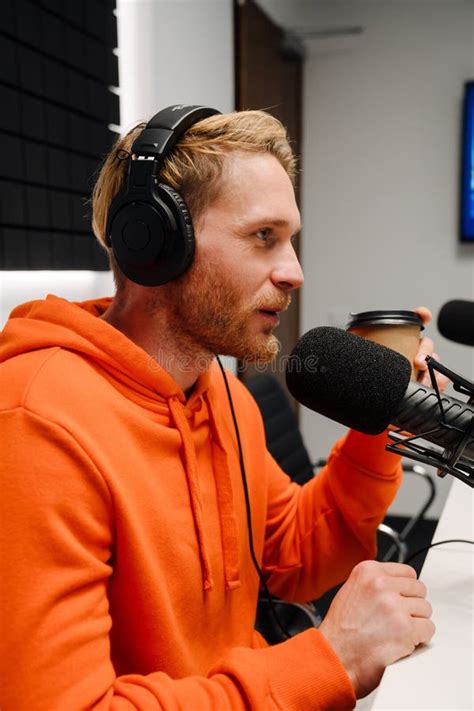 Young Male Radio Host Using Microphone While Broadcasting In Studio