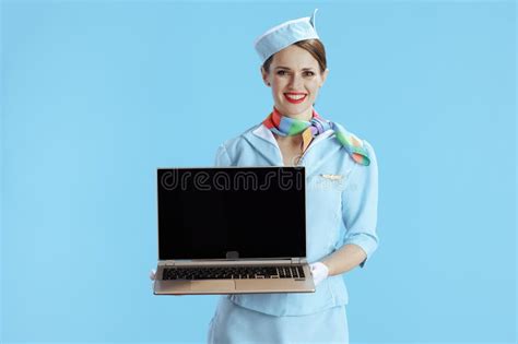 Female Flight Attendant On Blue Showing Laptop Blank Screen Stock Photo