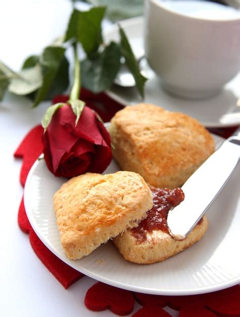 Scones en forma de corazón con mermelada de fresa y una taza de té