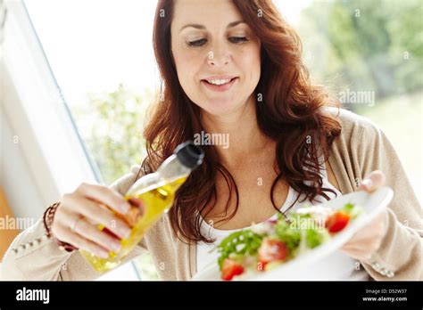 Woman Pouring Olive Oil Onto Salad Stock Photo Alamy