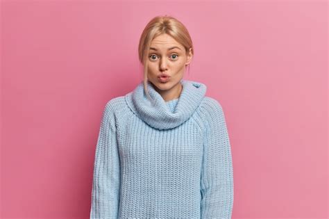 Schöne junge Frau ohne Make up blonde gekämmte Haare und blaue Augen schmollt Lippen und sieht