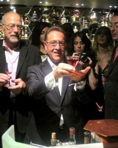 A Group Of People Standing Around Each Other Holding Wine Glasses