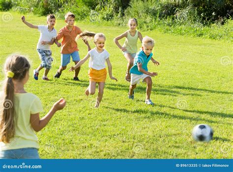 Bambini Che Danno Dei Calci Al Calcio In Parco Immagine Stock