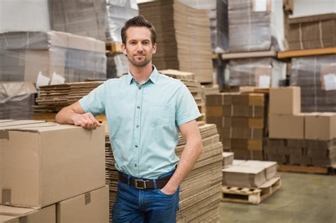 Premium Photo Smiling Warehouse Worker Leaning Against Boxes