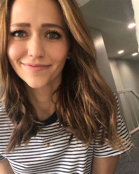 a close up of a person wearing a striped shirt and looking at the camera with a smile on her face