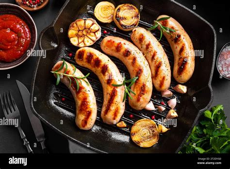 Gegrillte Würstchen mit Tomatensauce Gemüse und Kräutern auf schwarzer