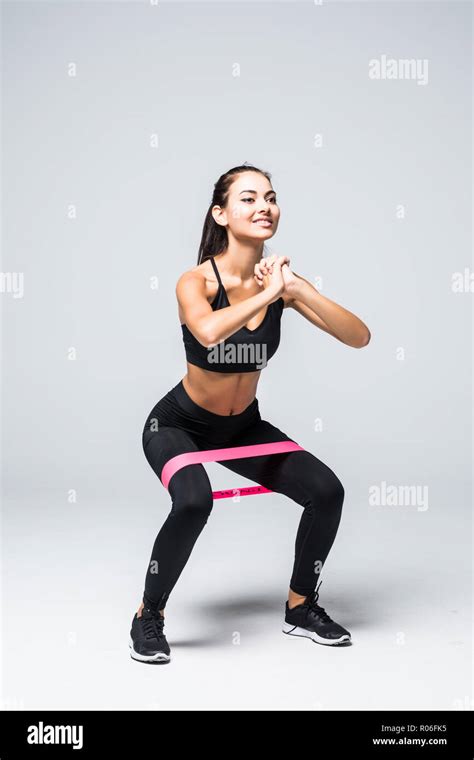 Slim Blonde Woman Doing Squats With Fitness Loop Band Isolated On White Background Stock Photo