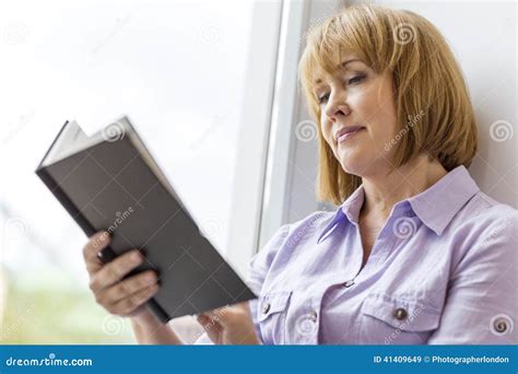 Mature Woman Reading Book By Window At Home Stock Image Image Of Woman Short