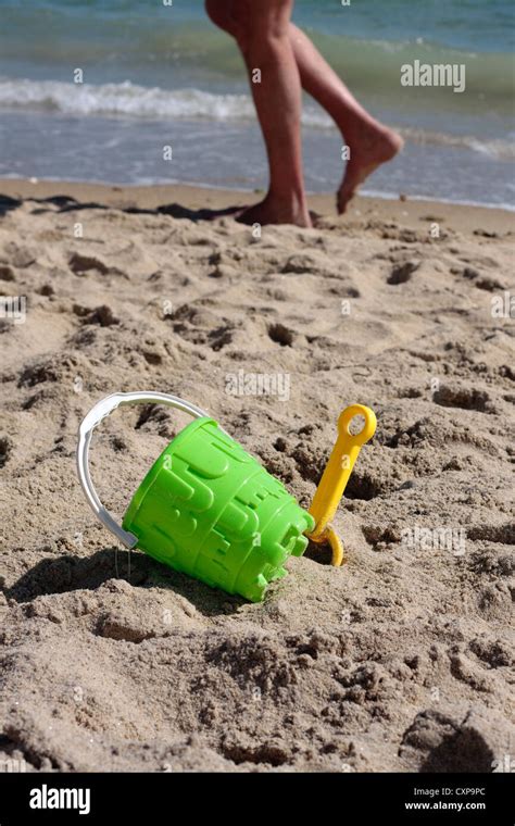 Bucket And Spade On Beach With Person Walking Past Stock Photo Alamy