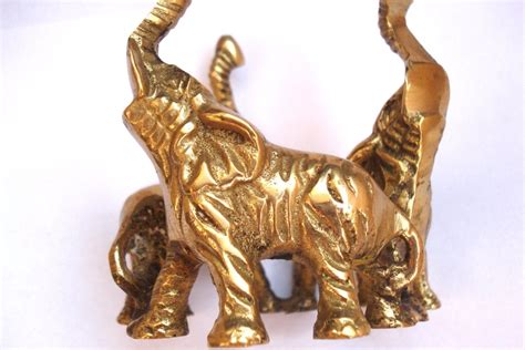 Shiny Brass Elephant Figurines Standing Tall With Their Trunks Up The