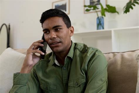 Premium Photo Happy Biracial Man Sitting On Sofa Talking On