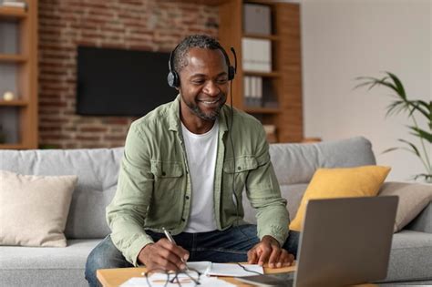 Um Afro Americano Sorridente De Meia Idade Em Fones De Ouvido Olha Para