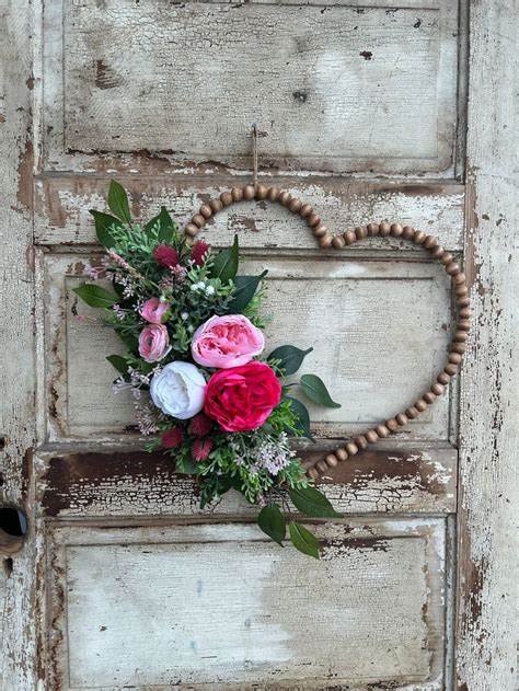 A Heart Shaped Wreath With Pink And White Flowers Hanging On An Old