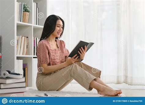 Happy Contented Young Woman Relaxing Reading A Book On The Floor Stock