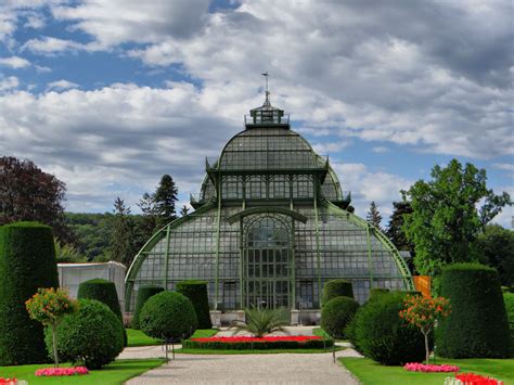 A Large Glass House Surrounded By Lush Green Trees And Flowers In The