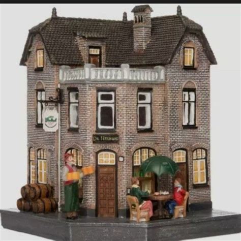 A Small Model Of A Building With People Sitting Outside