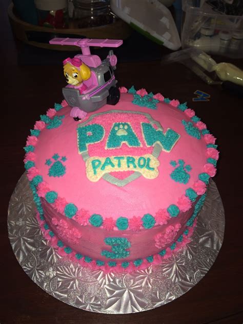 A Pink Cake With Paw Patrol Frosting Sitting On Top Of A Glass Platter