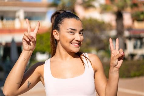 Mujer Morena Bonita Joven Que Muestra El Signo De La Victoria Con Ambas