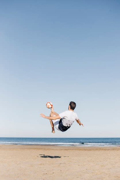 Kerl Der Fu Ball Am Strand Spielt Kostenlose Foto