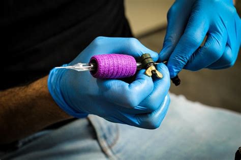 Tatuador luvas de látex azul preparando a agulha e a máquina de