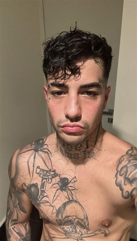 A Man With Tattoos On His Chest Looking At The Camera While He Is