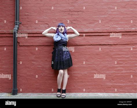 Sassy Alternative Woman Wearing Black Dress Has Purple Hair Leaning