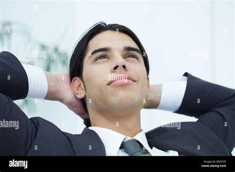 Young Businessman Leaning Back With Hands Behind Head Looking Up