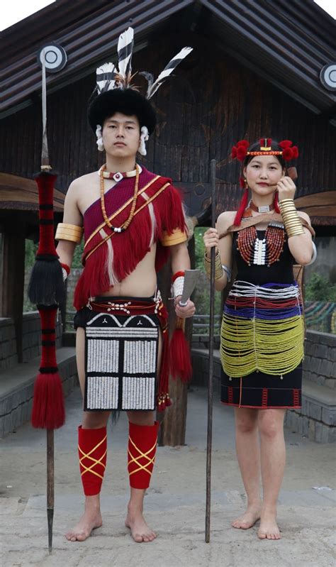 Two People Dressed In Native Garb Standing Next To Each Other With