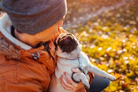 Master Holding Pug Dog In Hands In Autumn Park Happy Puppy Looking On