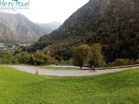 A Person Riding A Bike Down A Winding Road In The Middle Of A Mountain