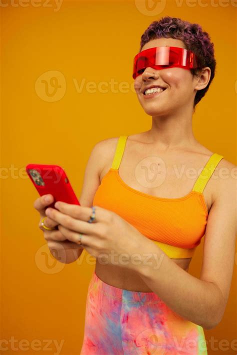 Woman Blogger Smiling In Unusual Red Millennial Glasses Holding Her Phone And Looking At The