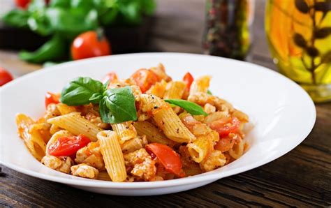 Penne Pasta En Salsa De Tomate Con Pollo Y Tomates En Una Mesa De Madera Foto Gratis