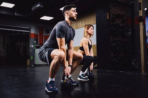 Premium Photo A Fitness Couple Doing Powerlift Exercises With Kettlebells In A Gym