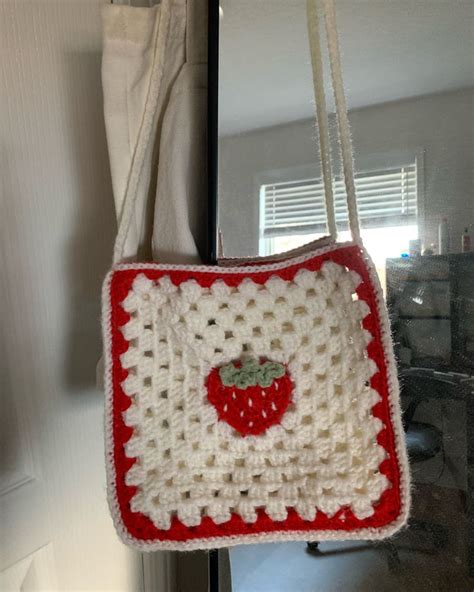 A Crocheted Strawberry Purse Hanging From A Hook