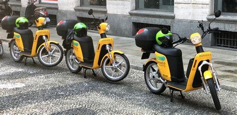 Several Motor Scooters Are Lined Up On The Street In Front Of A Building